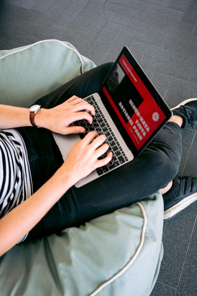 Person working remotely on a laptop while sitting comfortably on a beanbag chair indoors.